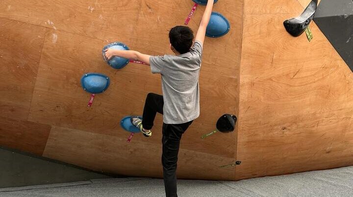 Ein bouldernder Junge an einer hölzernen Boulderwand | © Leonie Hoffmann